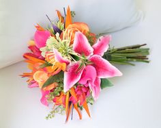 a bridal bouquet with orange and pink flowers on a white couch cushion, close up