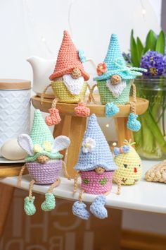 small crocheted gnomes hanging from hooks on a table