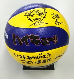 a yellow and blue ball with an anime character drawn on the side sitting on a black stand