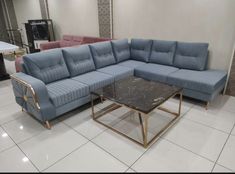 a blue sectional couch sitting on top of a white tiled floor next to a coffee table