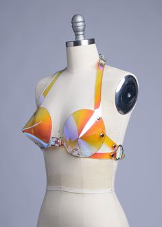 This bullet bra, or "cone bra" is inspired by retro pin-up vixens. This is the iridescent holographic version! Halter style straps. Buckles in front, back, and behind the neck. Silver-toned nickel plated hardware. Holes reinforced with grommets. Available in Sunset PVC (shown) or Blue PVC. Both colors are transparent. Sunset shifts warm over light colors, shifts blue over darker colors. Blue shifts cool over light colors, and warm over darker colors. Fits up to a DD cup - custom sizing available Futuristic Photoshoot, Futuristic Costume, Bra Art, Alien Clothes, Bullet Bra, Retro Pin Up, Seductive Clothes, Mood Board Fashion, Festival Looks