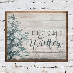 a wooden sign that says welcome winter with a pine tree in the center on a white brick wall