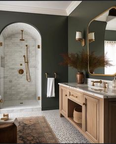 a bathroom with green walls and marble counter tops, gold fixtures and an oval mirror