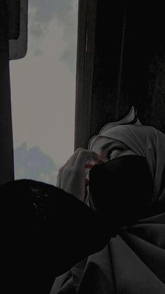 a person with a head covering is looking out the window