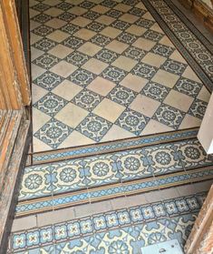 an ornate tile floor with blue and white designs on it's sides, next to a doorway