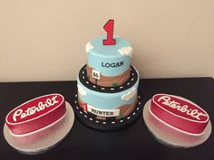 three tiered birthday cake with the number one on top and two smaller cakes below