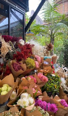 a bunch of flowers that are sitting on the ground in front of a store window