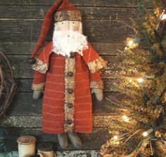 an old fashioned santa clause doll sitting next to a christmas tree