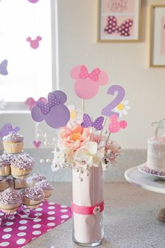 a vase filled with flowers and cupcakes on top of a table