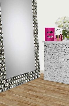 a large mirror sitting on top of a wooden floor next to a dresser and vase