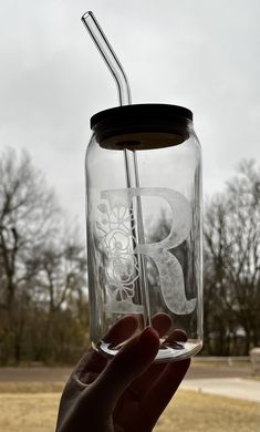 a person holding up a glass jar with a straw in it and the lid is empty