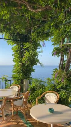 an outdoor patio with tables and chairs overlooking the ocean