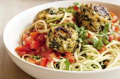 a white bowl filled with pasta and meatballs on top of a wooden table next to a fork