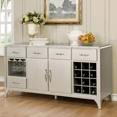 a white cabinet with wine bottles and vases on it in front of a painting