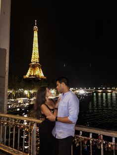 a man and woman standing next to each other in front of the eiffel tower