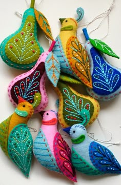 several colorful ornaments are hanging on a white surface with strings attached to them, including one bird and two birds