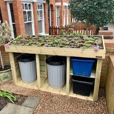 an outdoor planter with two trash cans and plants growing out of the top, in front of a brick building