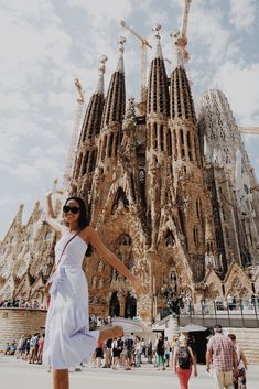 a woman standing in front of a very tall building that has many spires on it