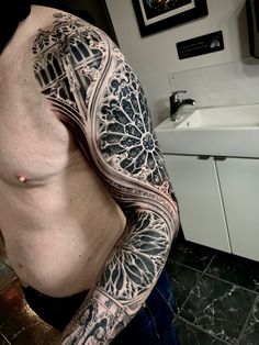 a man with a tattoo on his arm and chest standing in front of a sink