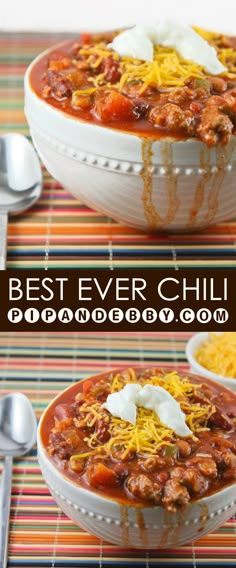 two bowls filled with chili and cheese on top of a striped table cloth next to spoons