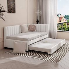 a white couch sitting on top of a hard wood floor next to a large window