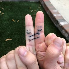 two fingers with faces drawn on them are pointing to each other in front of the camera