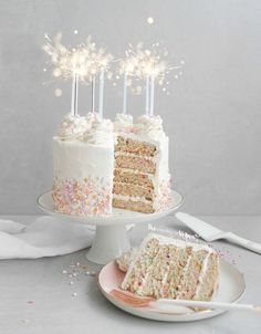 a cake with white frosting and sprinkles on it, next to a slice