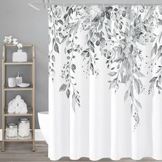 a shower curtain with flowers and leaves on it in a gray bathroom, next to a shelf full of toiletries