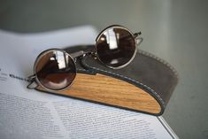 a pair of sunglasses sitting on top of a wooden case next to an open book