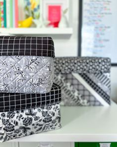 three black and white quilted boxes sitting on top of a desk