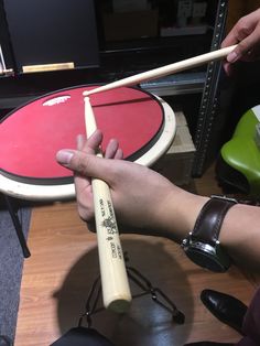 a person is holding two drumsticks in front of a drum set on a table