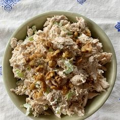 a green bowl filled with chicken salad on top of a blue and white table cloth