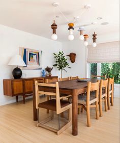 the dining room table is surrounded by wooden chairs and modern lighting fixtures, along with artwork on the wall