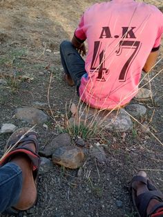 a person sitting on the ground next to some rocks