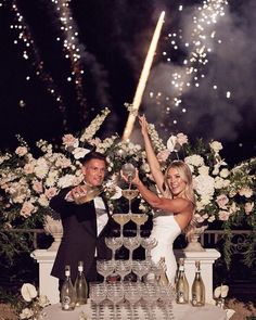 a man and woman standing next to each other in front of fireworks