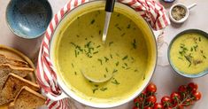 a bowl filled with soup next to bread and tomatoes