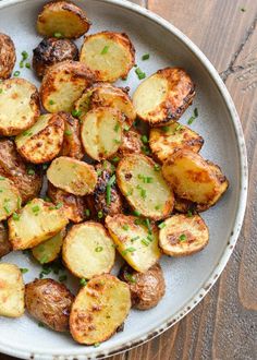 a white bowl filled with cooked potatoes on top of a wooden table