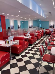 an empty restaurant with checkered floor and red booth seating, people are sitting at the tables