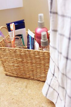 a basket with toothbrushes, shampoo and lotion in it sitting on a bathroom counter