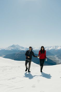 two people holding hands on top of a snow covered mountain