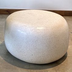 a large white round object sitting on top of a cement floor next to a wall