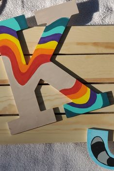 the letter k is made out of wood and painted with different colors on top of it