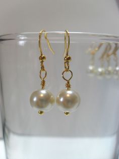 These dangling ivory pearl earrings are just lovely for your special day!   I will carefully wrap 8mm ivory faux pearls onto hypoallergenic gold-plated ear wires for genteel earrings that bob and sway just below the wearer's ears.  The ear wires are accented with a small round gold bead, and a smaller gold sphere peeks from below the pearls for a finished look.    These earrings match perfectly with my ivory pearl necklaces here: https://www.etsy.com/listing/186601986/ivory-pearl-and-gold-plate-bridesmaids?ref=shop_home_active_1 Classic Gold Hypoallergenic Pearl Earrings, Classic Pearl Bridal Earrings With Ear Wire, Cream Pearl Earrings For Formal Occasions, Classic Gold Bridal Earrings With Pearl Charm, Pearl Earrings With French Hook For Wedding, Classic Gold Dangle Pearl Earrings, Cream Pearl Earrings For Gift, Gift Cream Pearl Earrings, Elegant Cream Earrings With Ear Wire