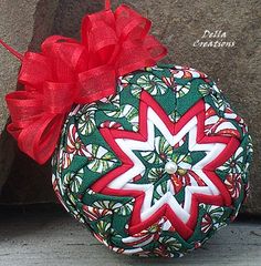 an ornament with a red bow on it sitting next to a stone wall