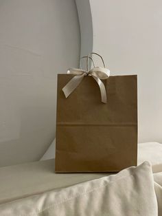 a brown paper bag sitting on top of a white bed next to a round mirror