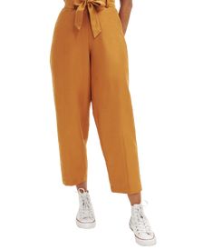 a woman is wearing an orange jumpsuit with a bow at the waist and white sneakers