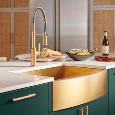 a kitchen with green cabinets and gold faucet