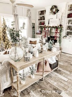 a living room filled with furniture and christmas decorations on top of a wooden table in front of a window