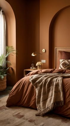 a bed with an orange comforter and pillows in a room that has arches on the walls