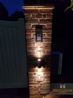 a brick wall with a light on it in front of a gated area at night